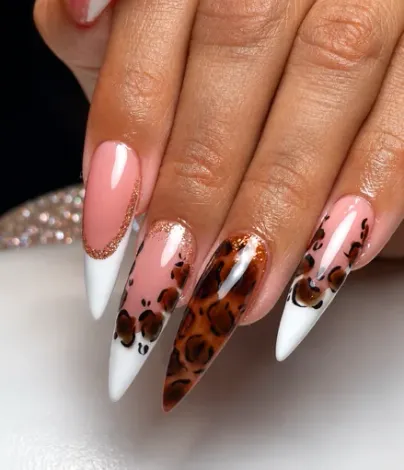 Uñas stiletto en rosa nude con puntas blancas y diseño de leopardo.