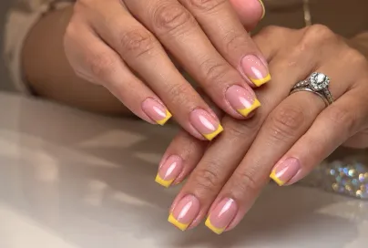 Manicura rosa con puntas amarillas, sobre una mesa del estudio.