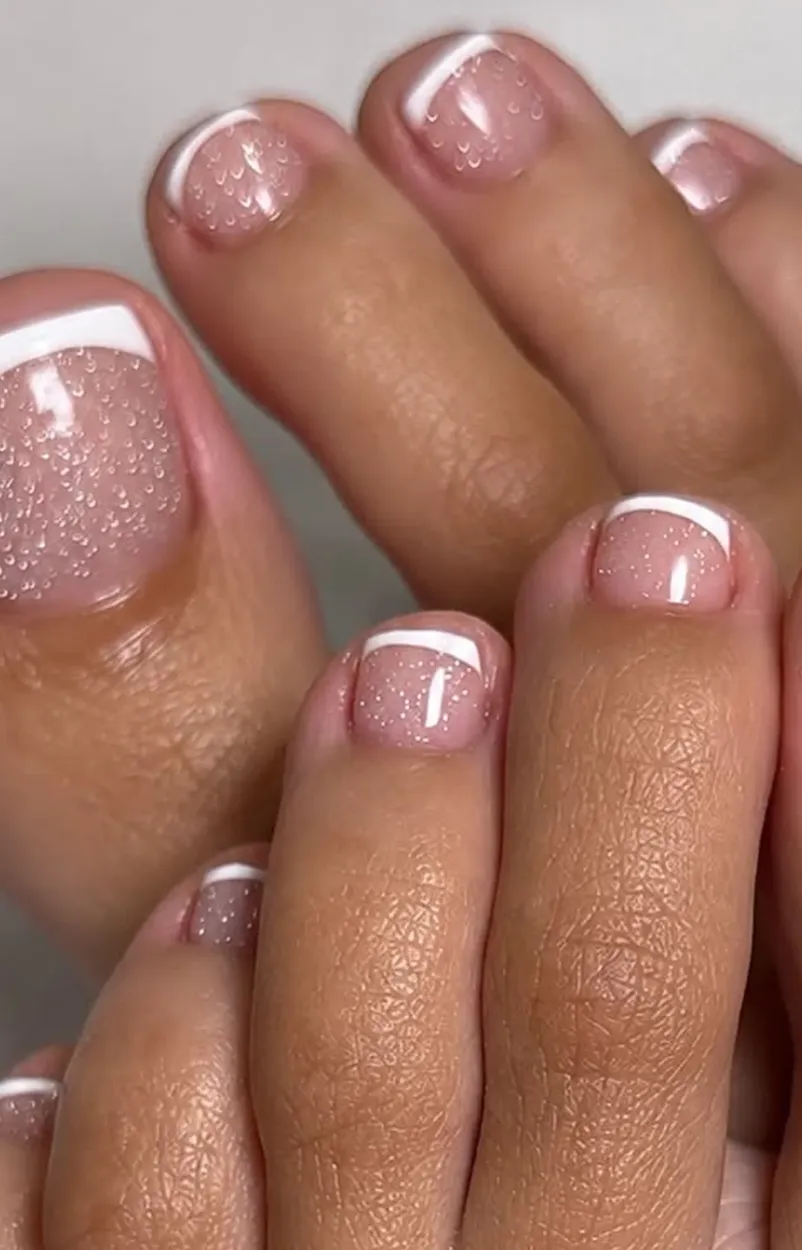 Pedicure francesa con brillo en las uñas de los pies.